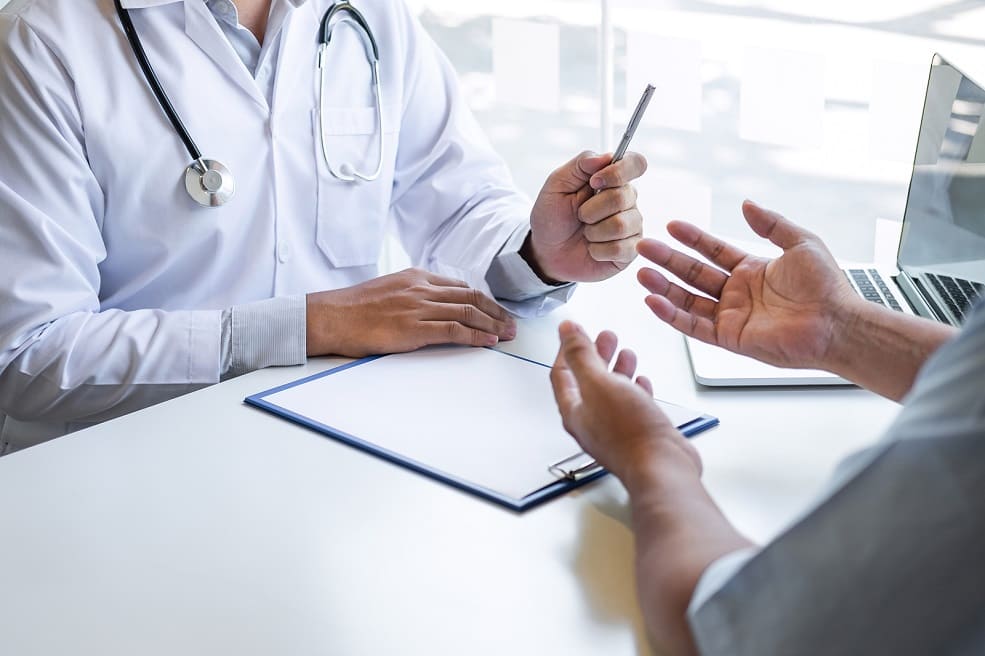 Arzt und Patient sitzen sich gegenüber und besprechen die Diagnose nach dem Bluttest bei Haarausfall