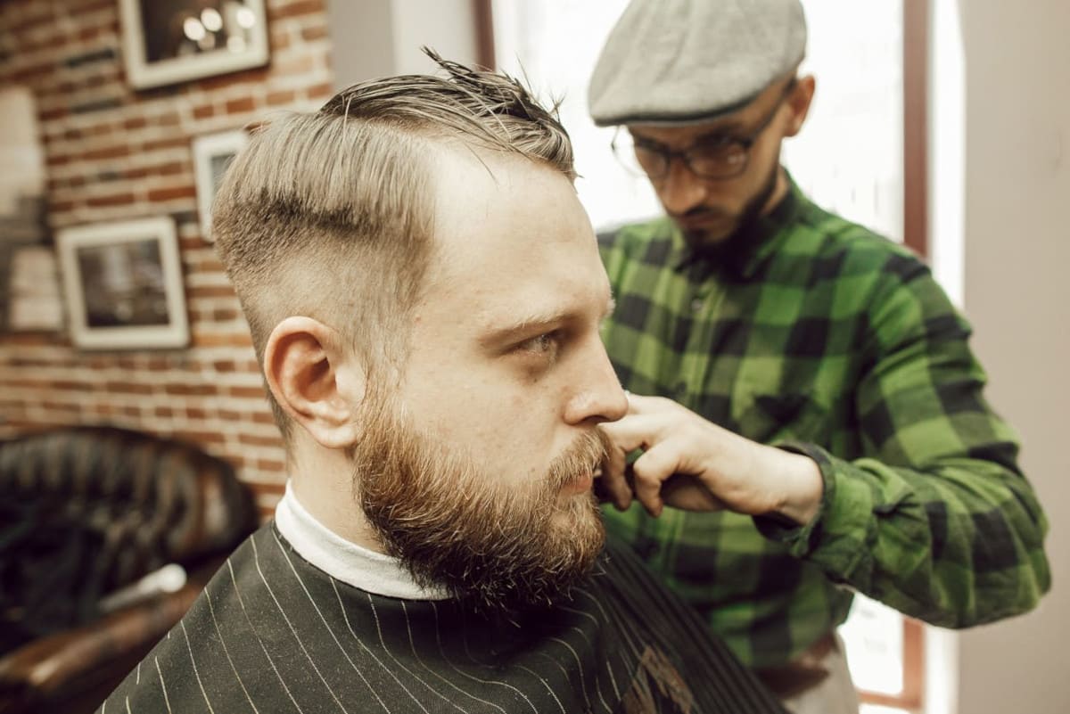 Mann lässt sich die Haare beim Friseur schneiden.