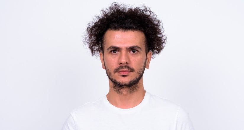 Mann mit locken guckt in die Kamera.