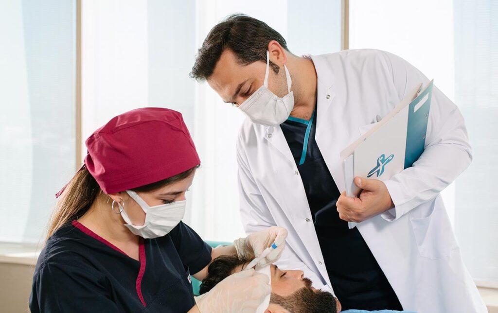 Dr Balwi mit Spezialistin bei der DHI Haartransplantation an einem Patienten