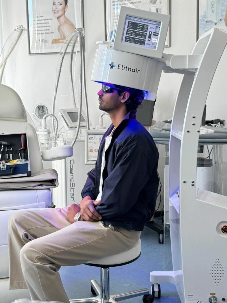 Patient sitzt während einer Low Level Lasertherapie mit blauem Licht in der Elithair Klinik Berlin