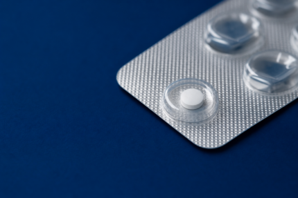 Einzelne Finasterid-1-mg-Tablette in einem Blister auf dunkelblauem Untergrund