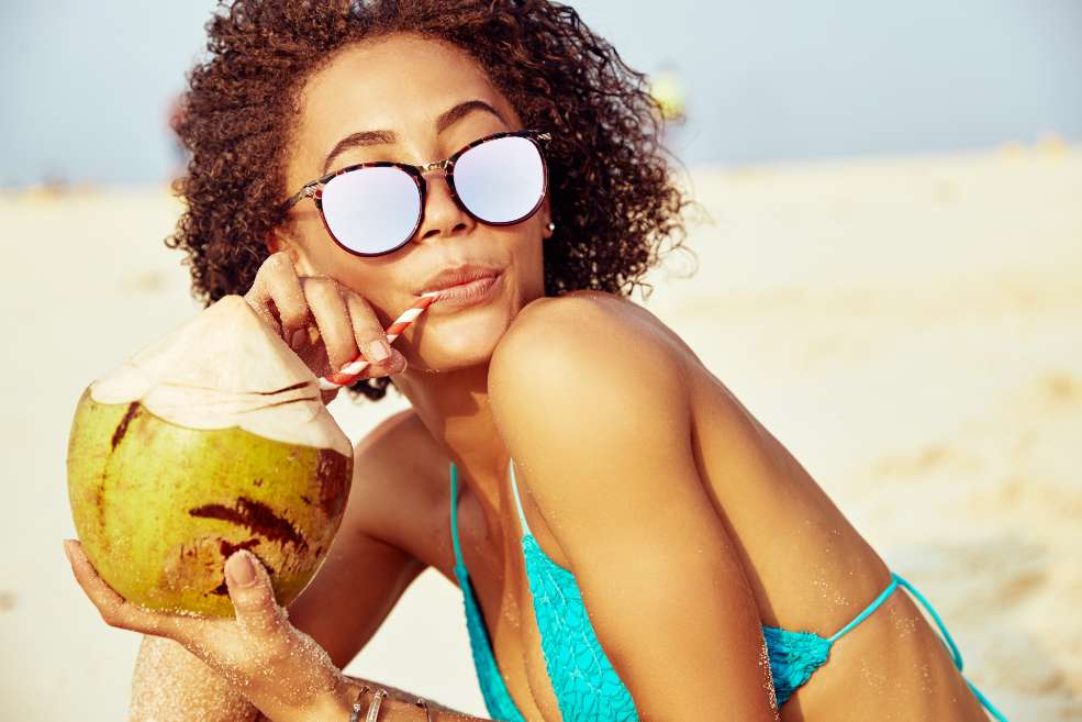 Mujer en la playa bebiendo agua de coco
