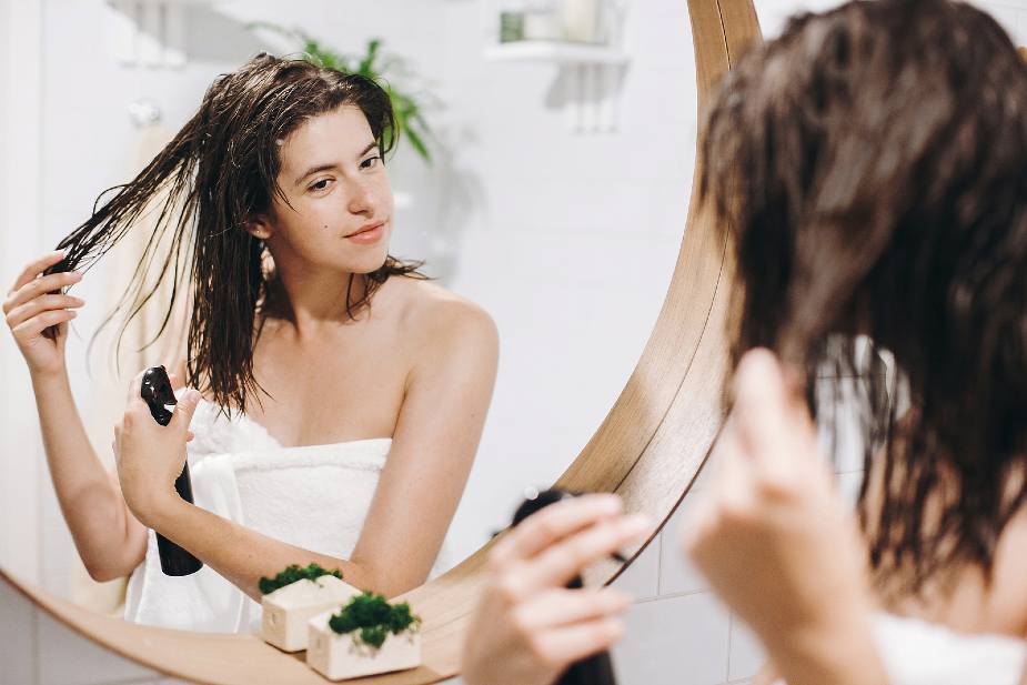 Mujer utilizando un spray de cabello en el baño