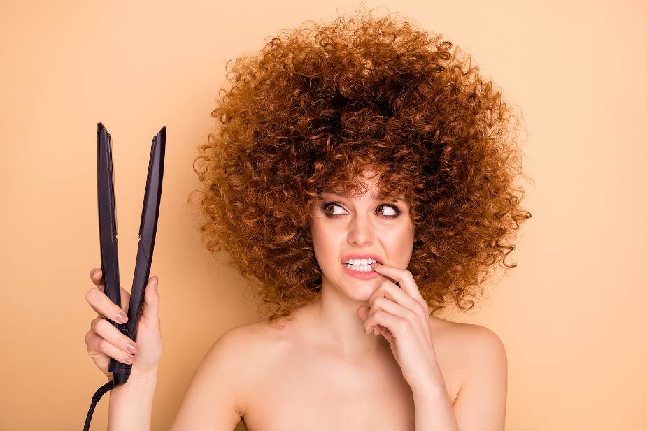 Mujer con pelo muy rizado sujetando una plancha en la mano