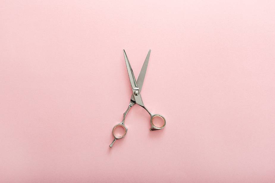 Tijeras de peluquero sobre fondo rosa