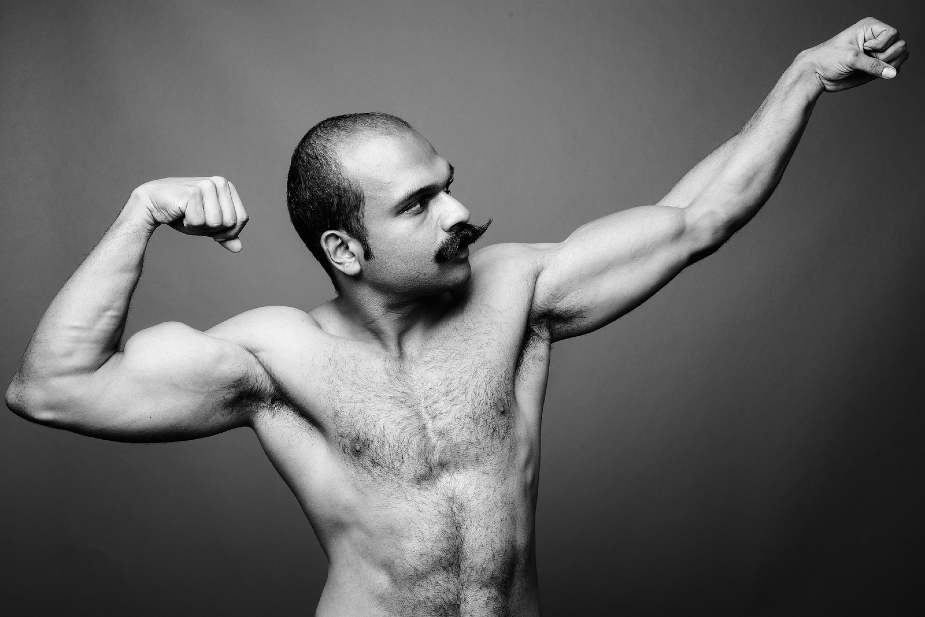 Hombre con calvicie y pecho poblado, marcando musculatura