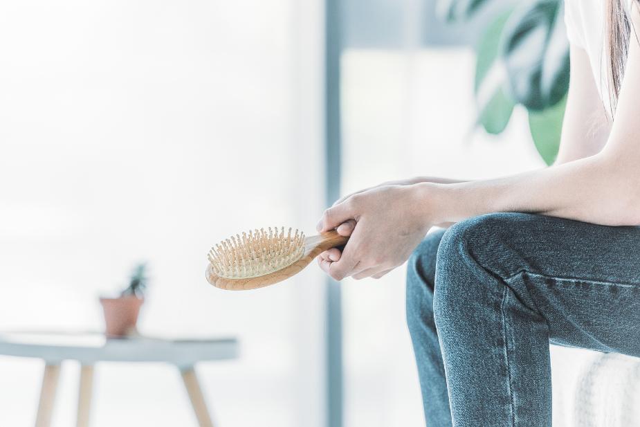 Mujer con pérdida de cabello según la escala Ludwig sosteniendo un cepillo