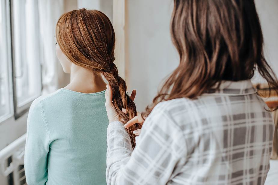 Mujer tranzando el cabello de otra mujer