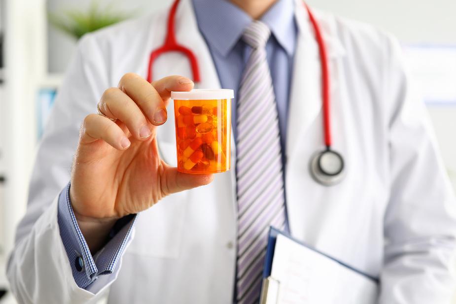 Médico sosteniendo un frasco de píldoras de Propecia.