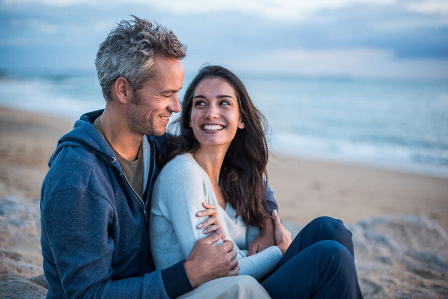 Hombre joven con canas en el pelo con su pareja en la playa