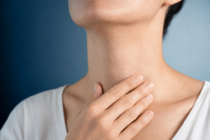 Persona se toca con calma la zona del cuello sobre la glándula tiroides, imagen serena de estética médica