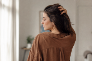 Junge Frau fährt sich nachdenklich durchs Haar, ruhige Stimmung, Sinnbild für Trichotillomanie und Genesung