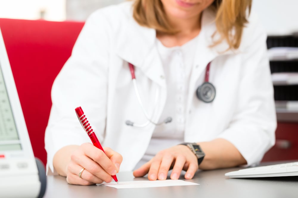 médecin rédigeant une prescription pour des analyses complémentaires au sujet d'une perte de cheveux