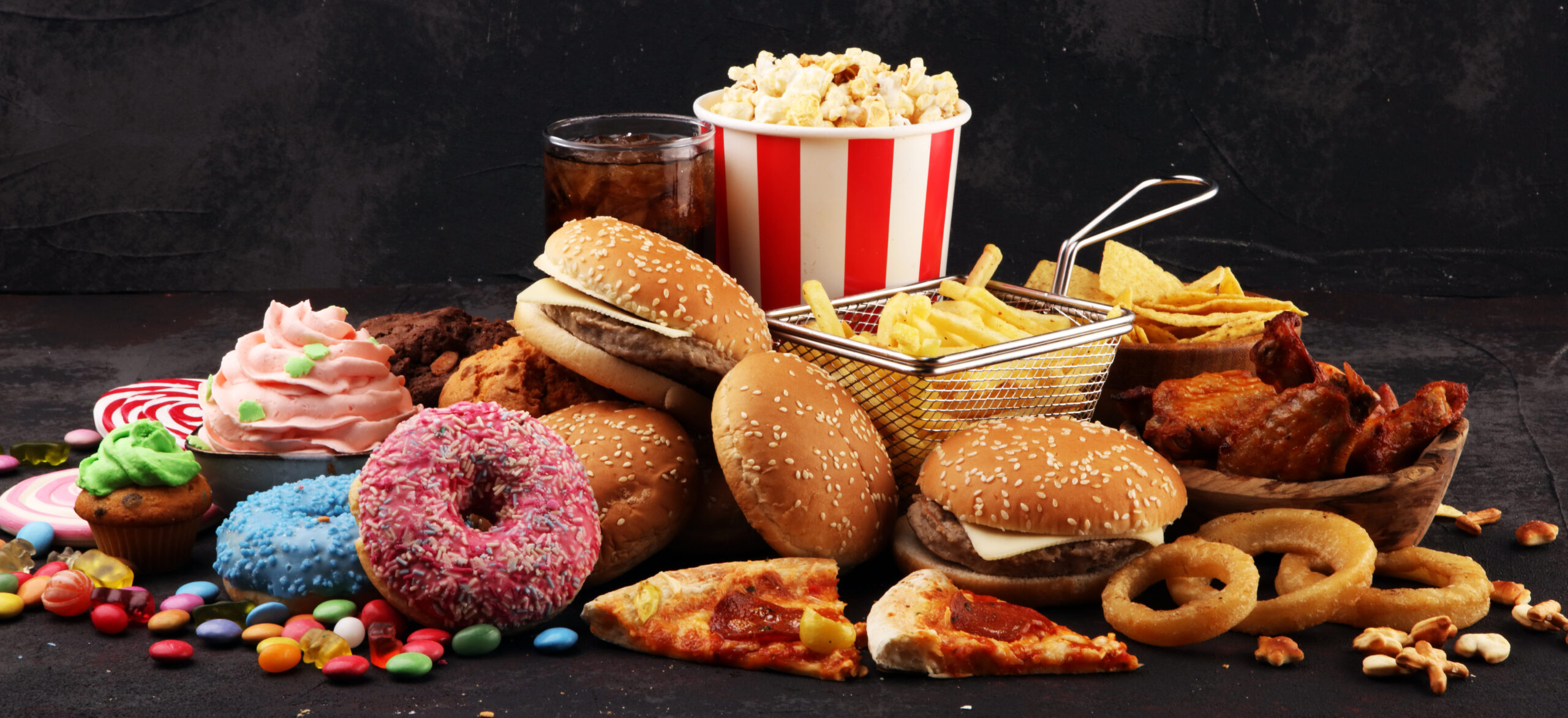 Une variété de fast-foods et de sucreries, dont des burgers, des pizzas, des beignets et des frites, qui représentent une alimentation malsaine et des habitudes alimentaires modernes.
