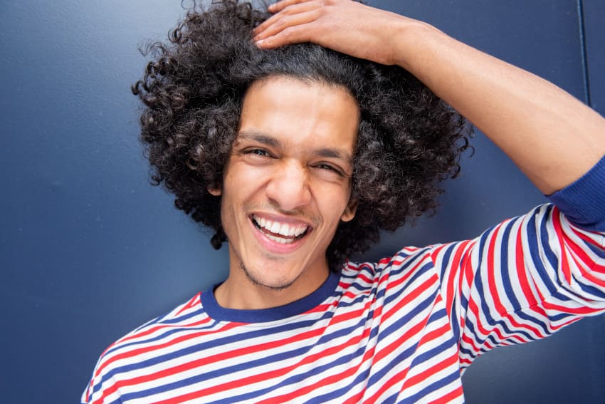 homme avec les cheveux frisés satisfait de sa greffe capillaire