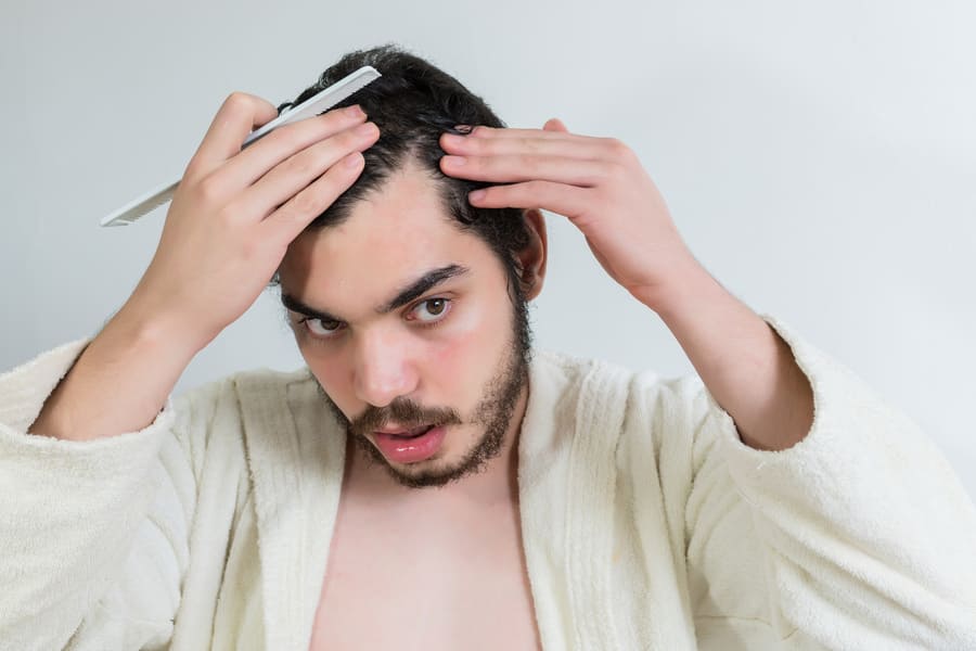 foto di un ragazzo preoccupato perché già stempiato a 20 anni