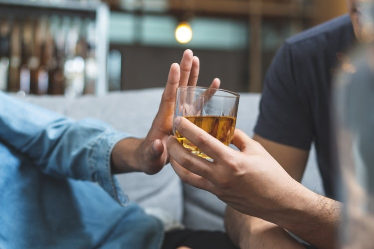 Uma pessoa recusa uma bebida alcoólica que lhe é oferecida