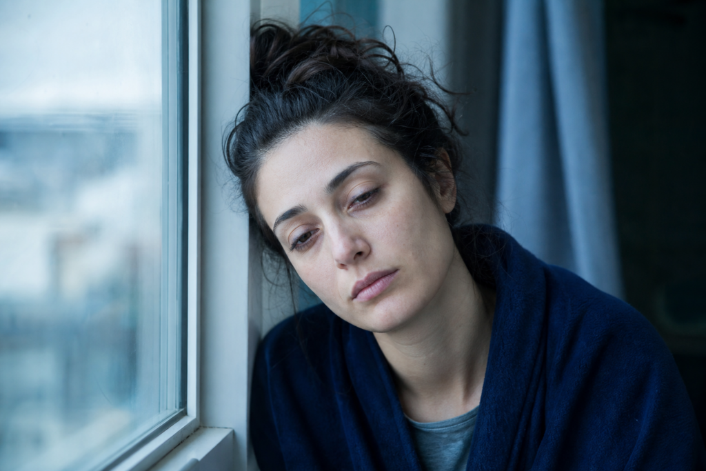 Erschöpfte Frau am Morgen am Fenster als Sinnbild für Müdigkeit bei Eisenmangel