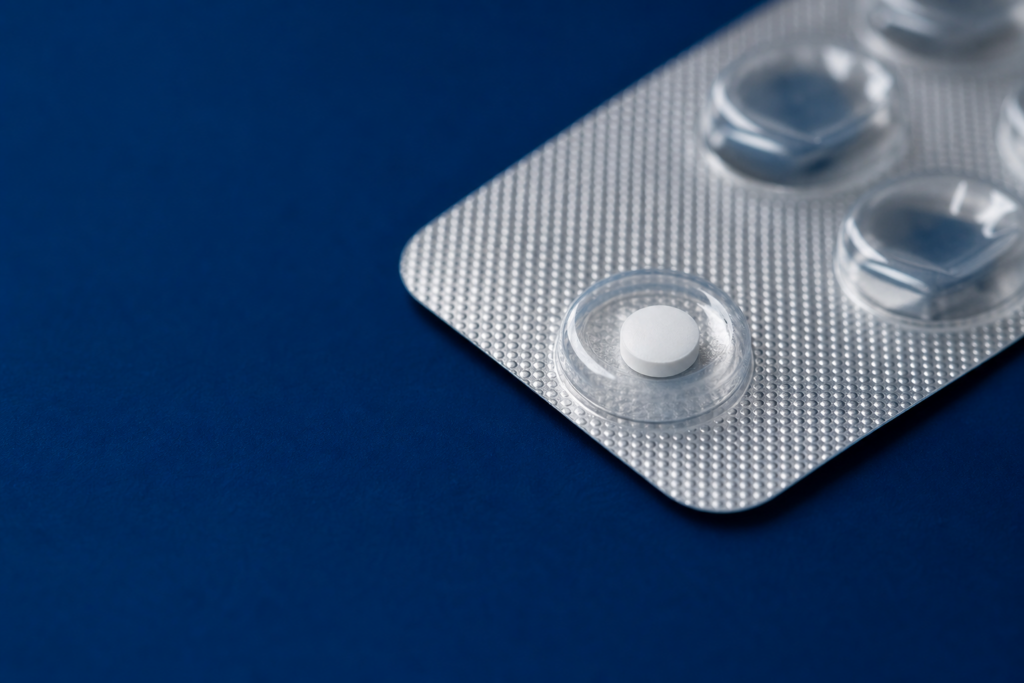 Einzelne Finasterid-1-mg-Tablette in einem Blister auf dunkelblauem Untergrund