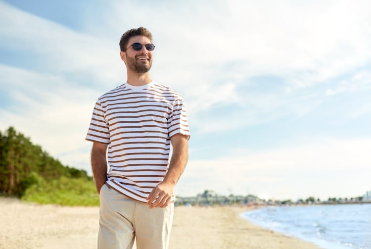 A man walking on a sunny beach in the Summer.