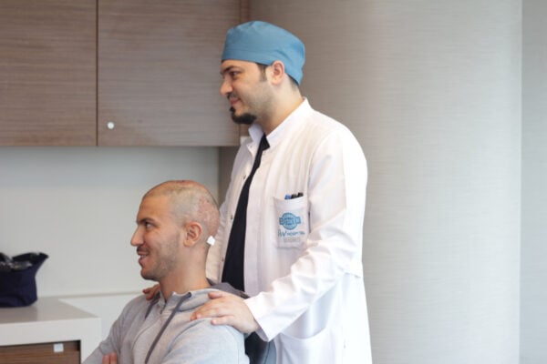 Picture of Dr Balwi examining a patient who has an androgenetic alopecia.