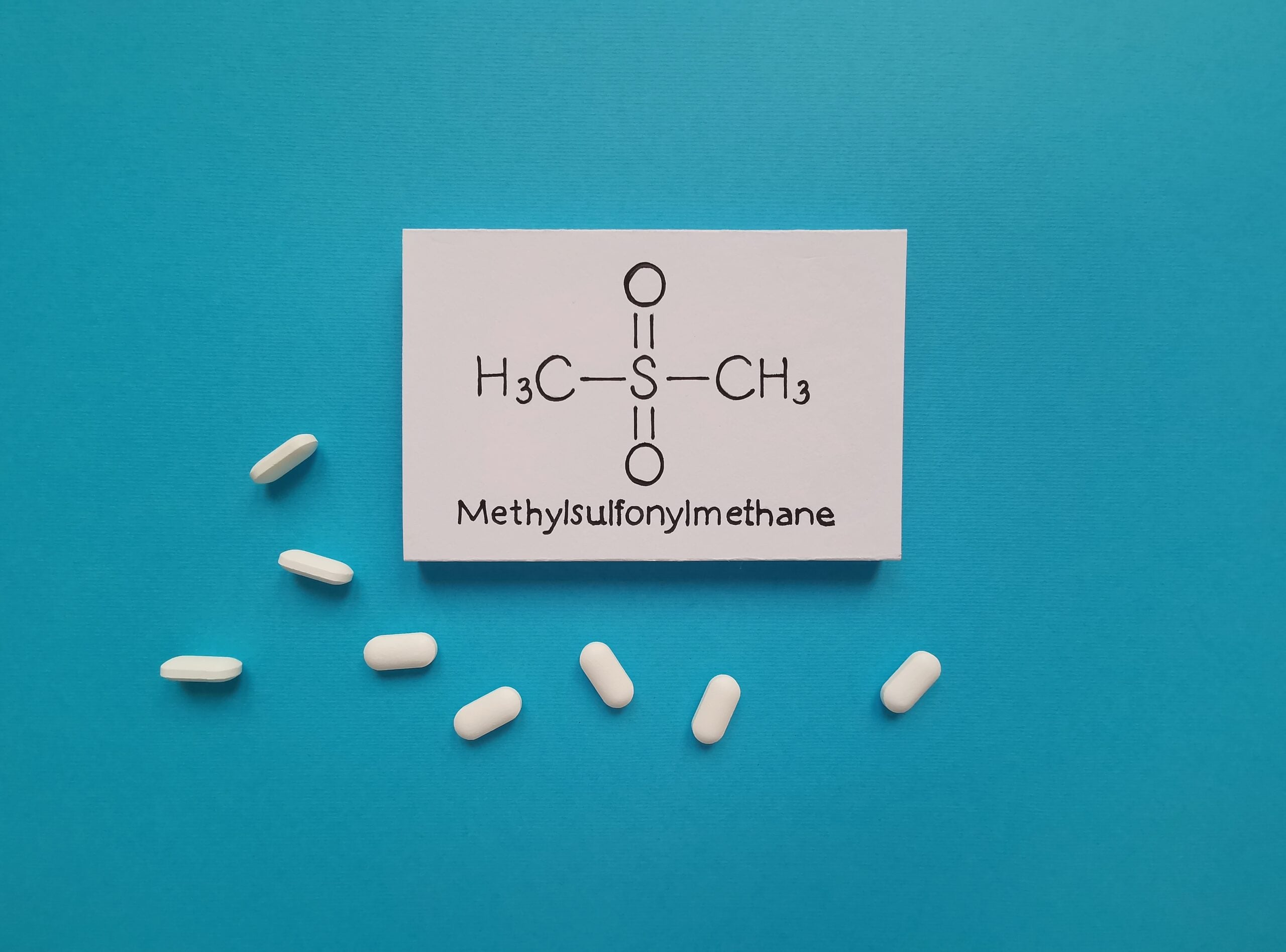 The chemical structure of methylsulfonylmethane surrounded by white MSM pills.