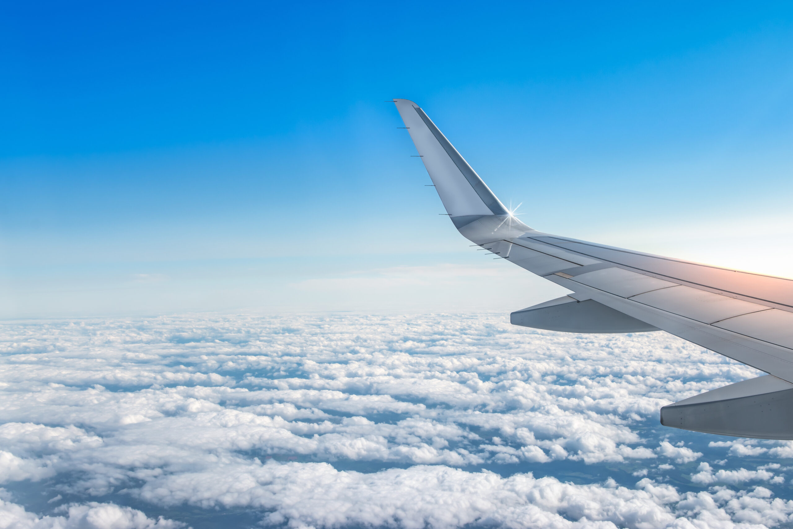 The wing of an airplane over a cloudy sky.