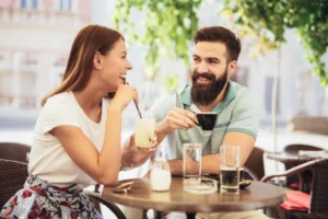 A smiling and laughing couple enjoying some drinks on their first date.
