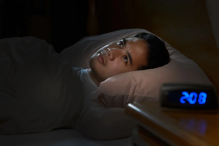 A person with insomnia lying awake in bed early in the morning.