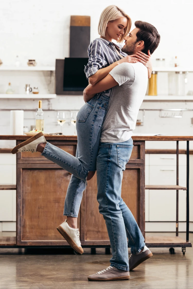 A couple passionately embracing in a kitchen.