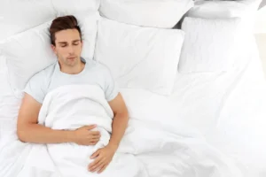 A man sleeping on his back with his head slightly elevated.