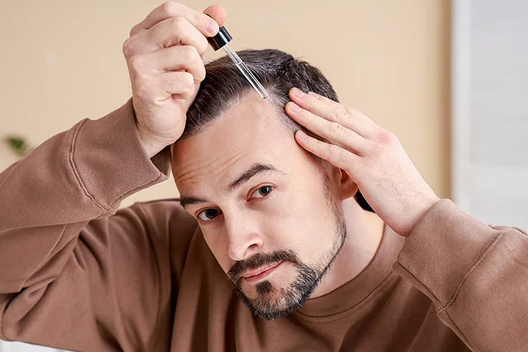 A man applies hair serum with a pipette.