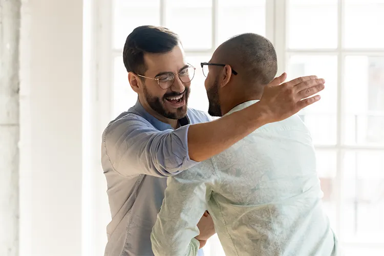 Two men hug one another.