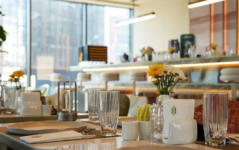 A small vase of white and yellow flowers on a dining table at the Elitoria Hotel