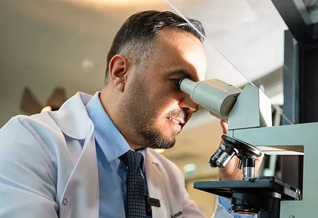 Dr Mustafa with Microscope in Clinical Research – Elithair