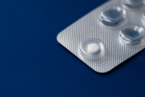 Einzelne Finasterid-1-mg-Tablette in einem Blister auf dunkelblauem Untergrund