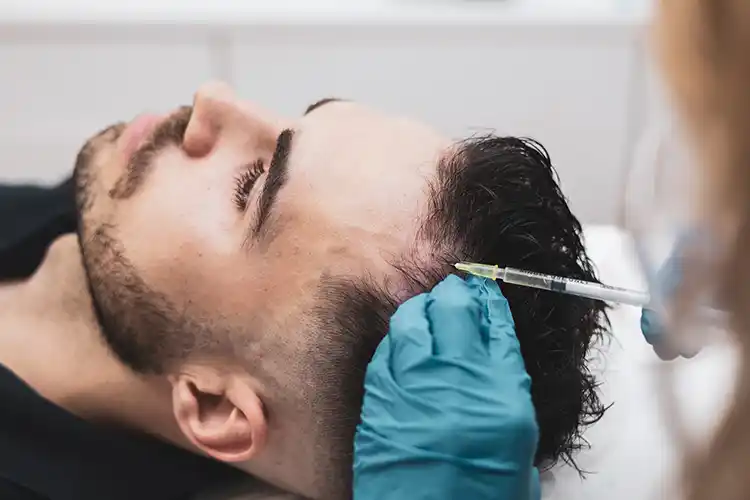 A man on a treatment table receiving PRP therapy via an injection into the scalp